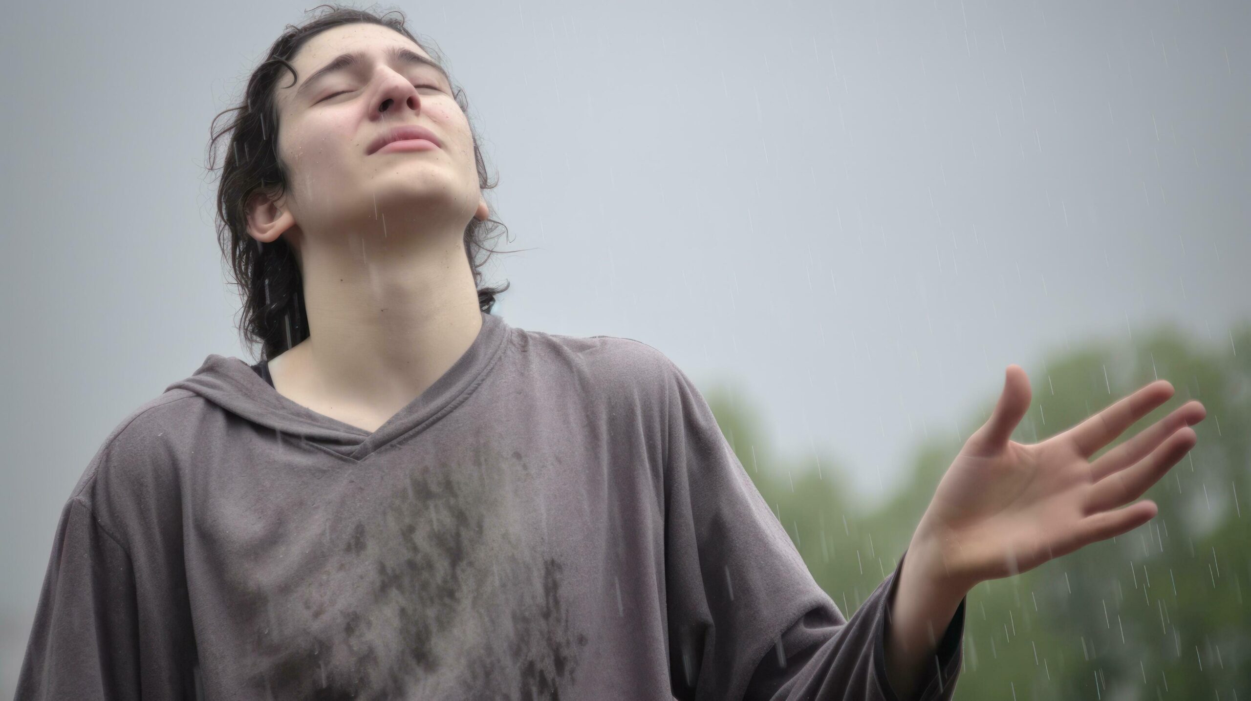 Ai-generated-a-young-man-stands-in-the-rain-with-his-hands-open-enjoying-the-moment-generative-ai-free-photo