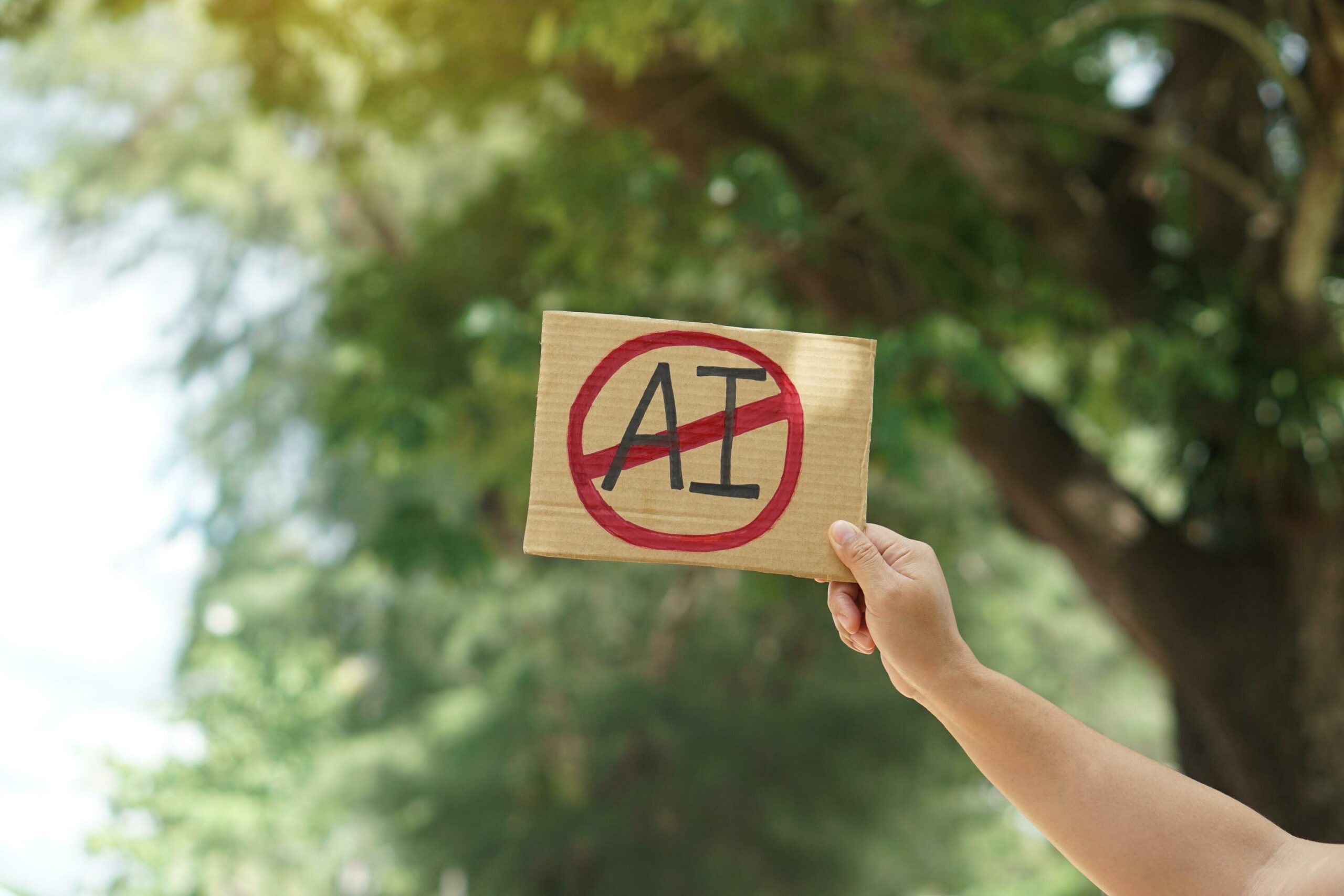 Close-up-hand-holds-paper-card-with-no-ai-prohibition-sign-outdoor-nature-background-concept-disagree-anti-or-don-t-support-to-use-ai-or-artificial-intelligence-in-daily-life-free-photo